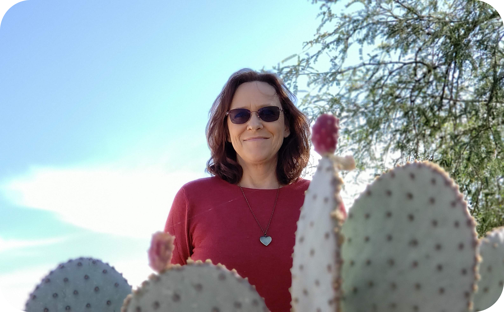 Person smiling behind prickly pear cactus